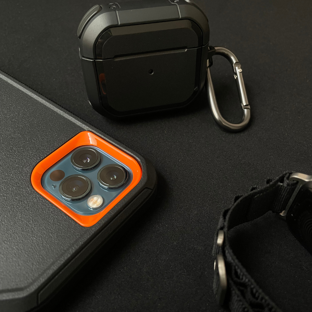 iPhone protective case Black orange near Airpods in protective case and applewatch with black fabric band